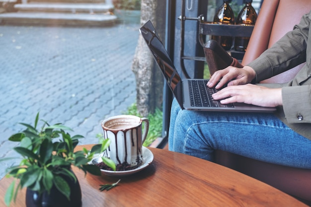 카페에 앉아있는 동안 노트북 키보드를 사용하고 입력하는 여자