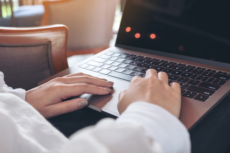 Photo woman using and typing on laptop with blank white desktop screen