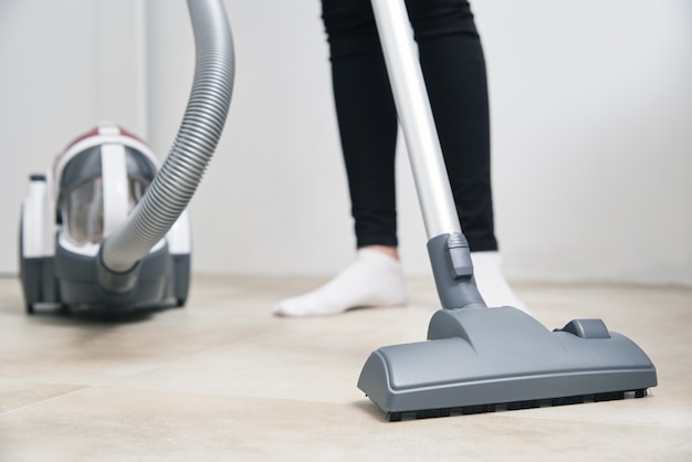 Woman using vacuum cleaner at floor