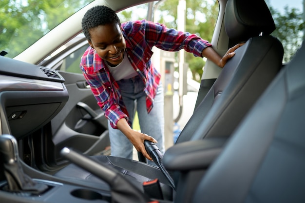 Woman using vacuum cleaner, hand car wash station