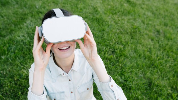 Woman using virtual reality glasses outside on a green grass