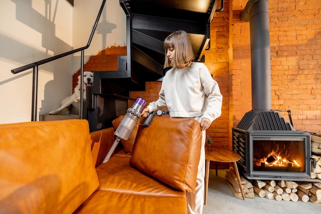 Woman vacuuming couch with wireless handheld vacuum cleaner