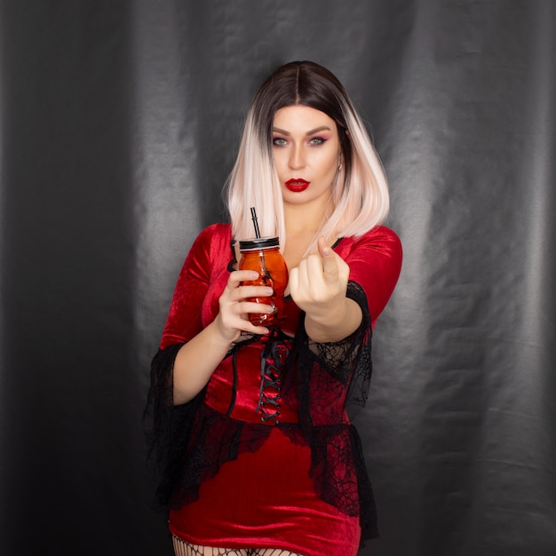 Woman in vampire dress holding a glass in the shape of a skull