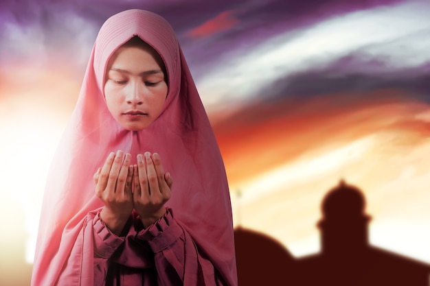 женщина в покрывале стоит, подняв руки и молясь