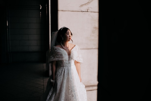 Photo woman in a veil stands in a shadow looking at the sun