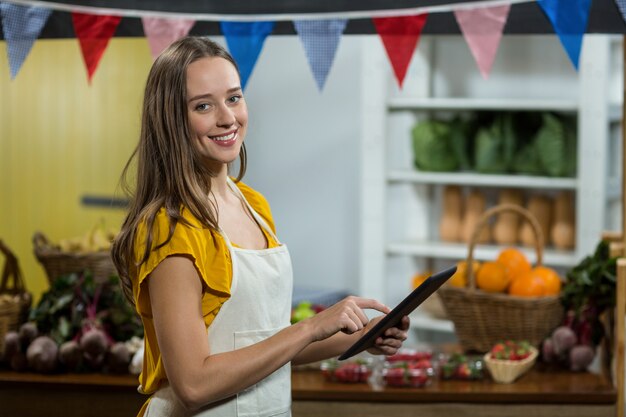 食料品店のカウンターでデジタルタブレットを使用して女性のベンダー