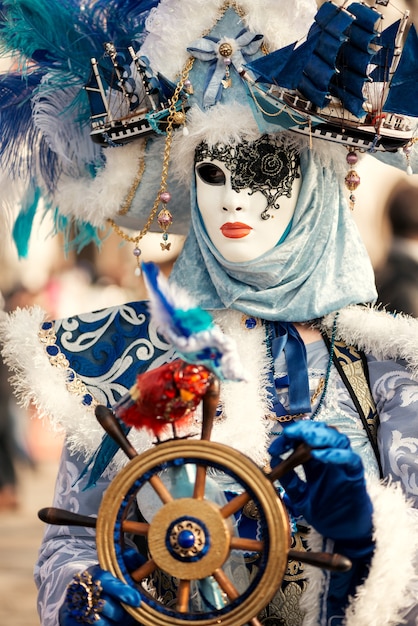 Photo woman in venetian carnival outfit holding steering wheel in hands marine concept