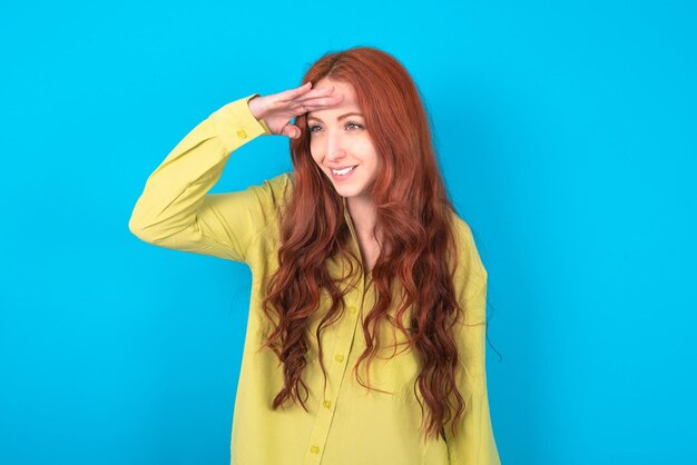 Woman very happy and smiling looking far away with hand over head searching concept