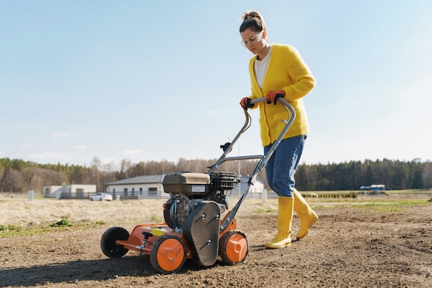 女性の村人は芝生や牧草地の乱切りと通気にエアレーター マシンを使用しています。