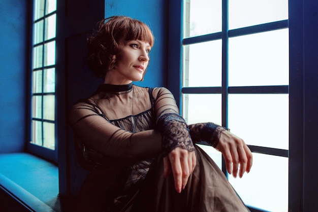 woman in vintage dress indoor by the window