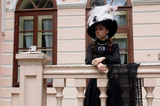 Woman in vintage dress on porch of castle