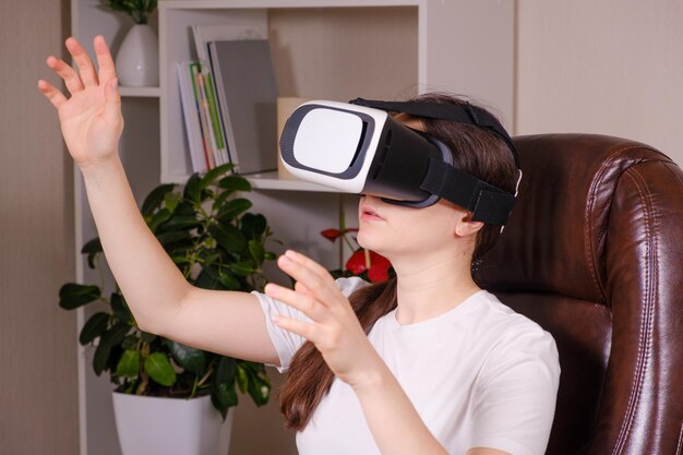 A woman in virtual reality glasses looks up against a gray background