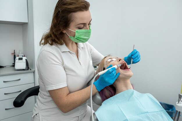 전문 치과 치료를 위해 치과를 방문하는 여성 여성 치과 의사가 환자를 구부립니다.