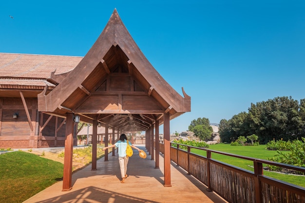 Woman visitor enters the wooden gate of an asian village decorated with oriental patterns