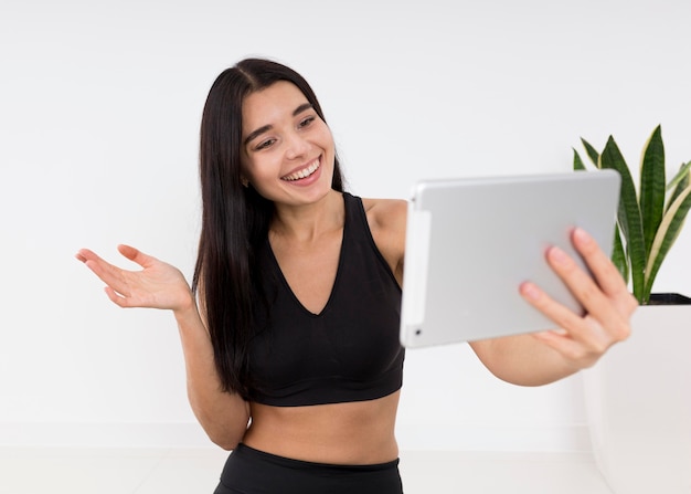 Photo woman vlogging at home with tablet while exercising