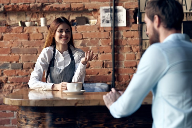 女性ウェイターがカフェのクライアントにコーヒーを持ってくる