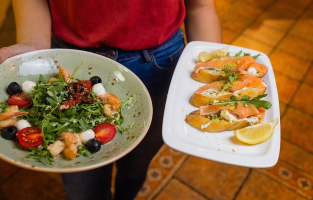 Woman waiter holding a wooden tray with bruschetta in her hand