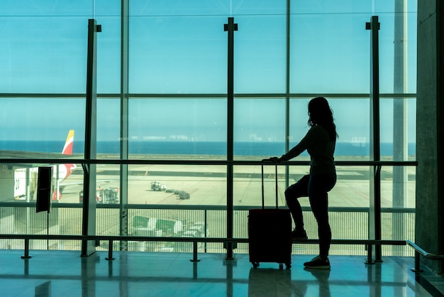 스마트폰을 사용하여 공항 터미널에서 비행기를 기다리는 여성 - 푸에르테벤투라 - 스페인