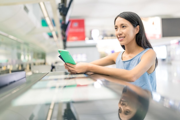 Woman waiting for check in and using mobile phone in the counter