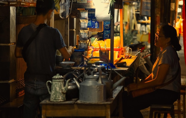 Photo woman waiting for her fried rice prepared on dark food stall in yogyakarta 2 february 2024