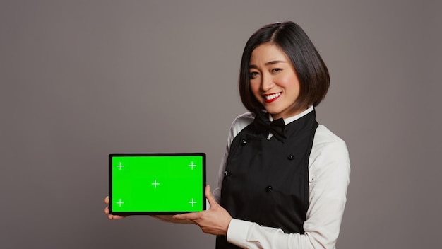 Woman waitress holding tablet with greenscreen display on camera