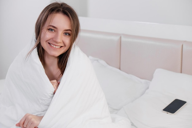 담요로 덮인 침대에서 아침에 일어나는 여자