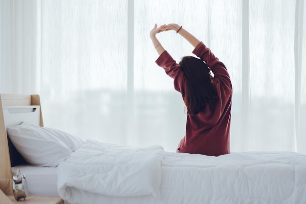 Donna che si sveglia al mattino allungando le braccia. donna felice si sveglia sul suo letto al mattino.