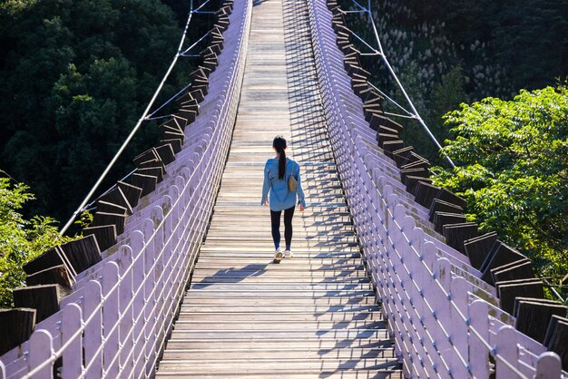 Женщина идет по подвесному мосту
