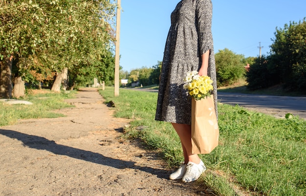 아름다운 꽃과 함께 공예 가방과 함께 가을 날에 산책하는 여자. 국화 꽃 에코 백.