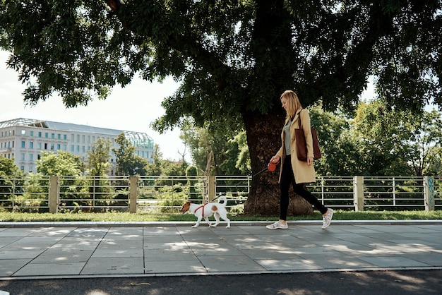 Фото Женщина гуляет со своей собакой на городской улице в летний день
