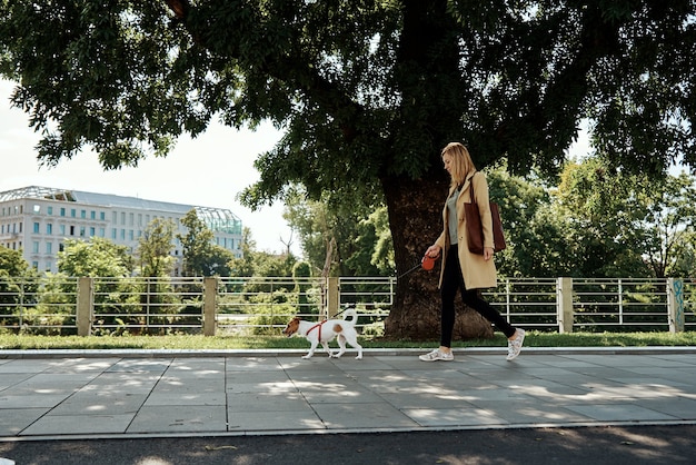 Woman walk with her dog at city street in summer day