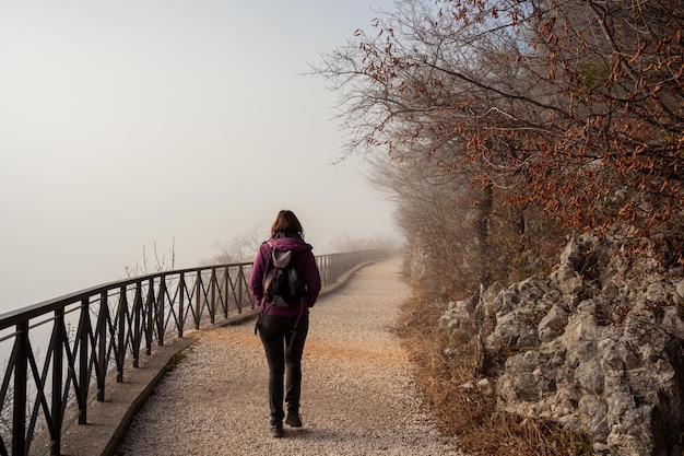 Donna che cammina da sola sul sentiero nebbioso rurale