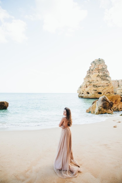 Woman walking along the beach against the rocks and ocean