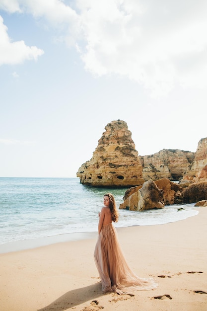 Woman walking along the beach against the rocks and ocean