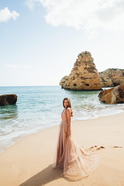 Woman walking along the beach against the rocks and ocean