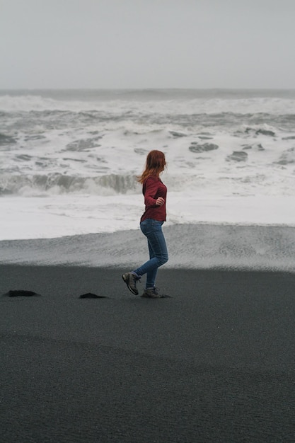 Woman walking along black Iceland beach scenic photography