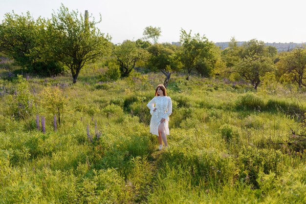 Photo a woman walking around lupine flowers and a tree in a park