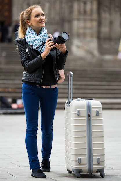 Foto donna che cammina nella città di autunno con la macchina fotografica digitale