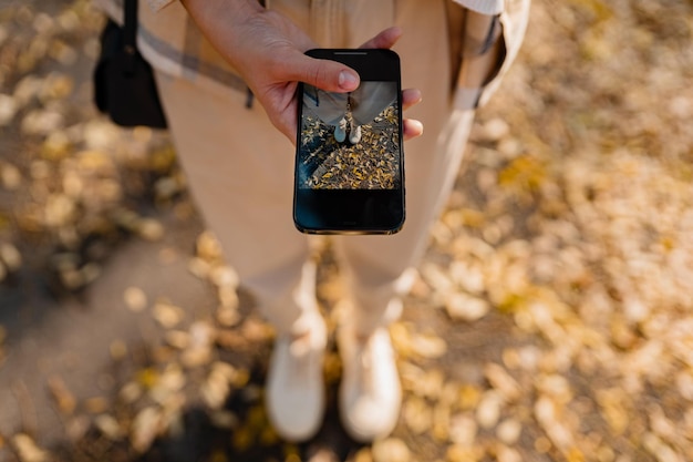 Donna che cammina in autunno tramite telefono