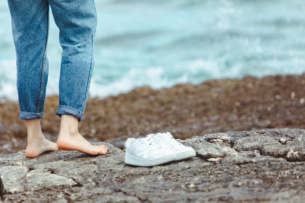 Женщина ходит босиком по берегу моря, держась за руки в белых туфлях, летние каникулы, союз природы