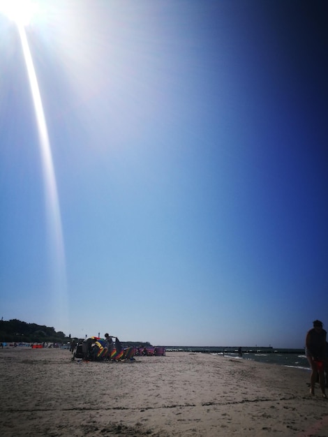 Woman walking at beach against blue sky