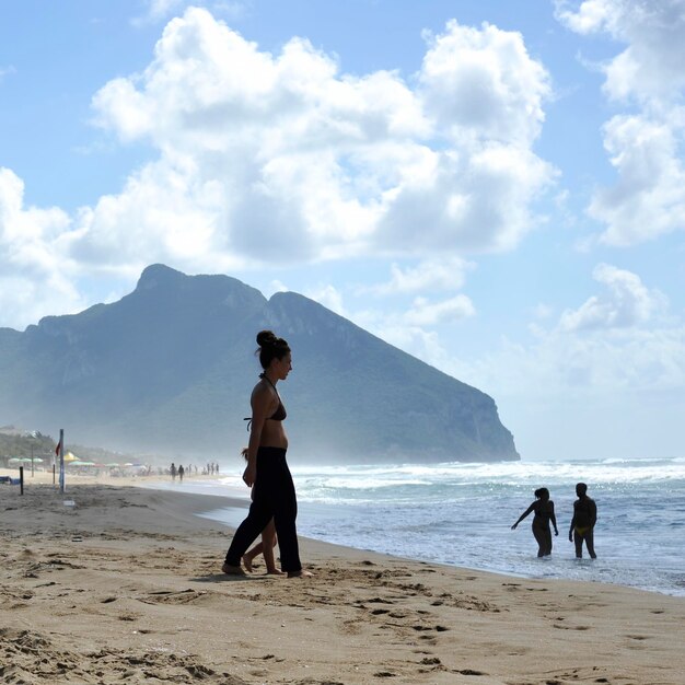 Woman walking at beach against sky