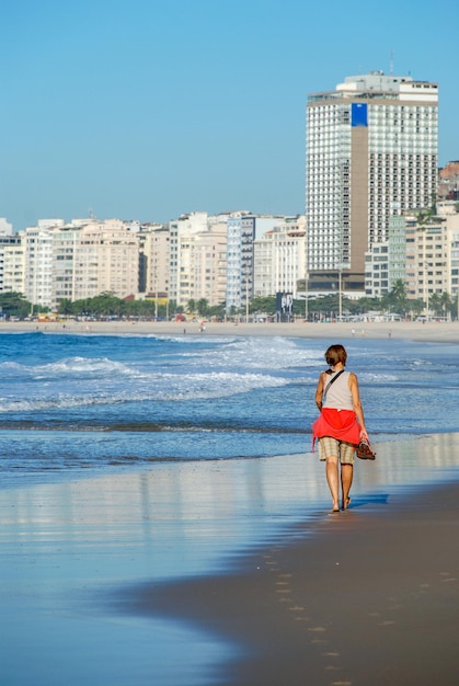 Donna che cammina sulla spiaggia di copacabana, rio de janeirodonna che cammina sulla spiaggia di copacabana, rio de janeiro