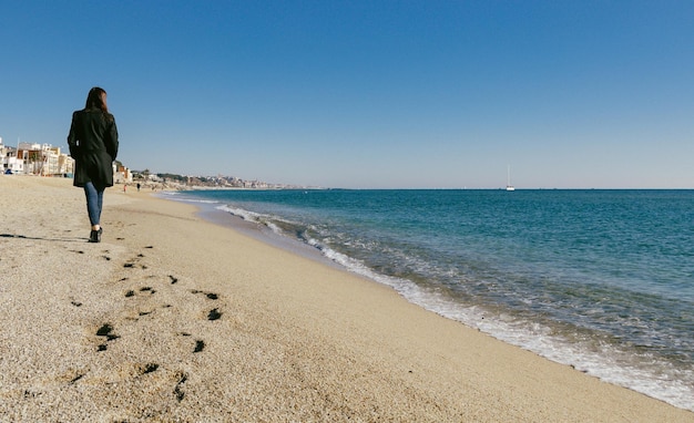 Woman walking on the beach on a sunny winter day