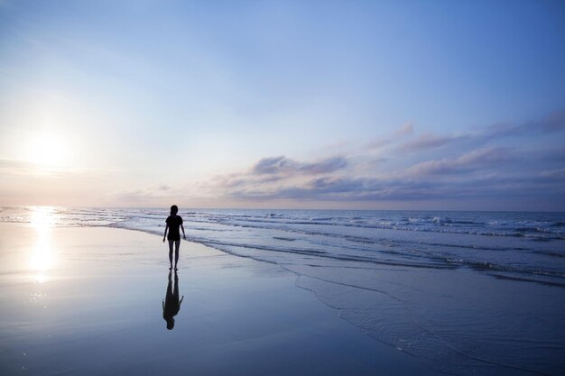 Photo woman walking on beach at sunrise