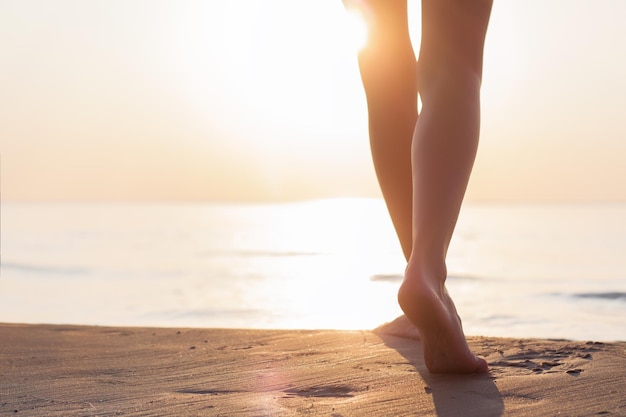 Woman walking on the beach at sunset