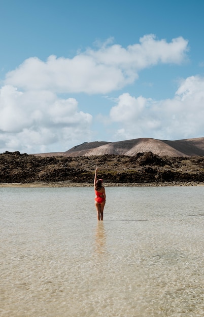 Donna che cammina sulla spiaggia e rocce vulcaniche