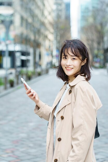 スマートフォンを手にビジネス街を歩く女性