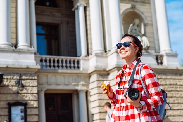 Woman walking by city with camera and ice cream copy space