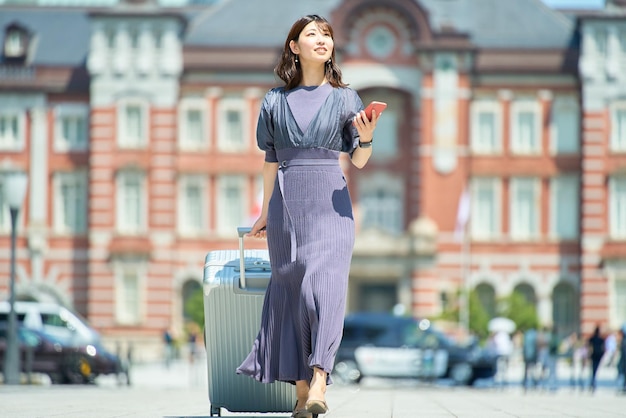 晴れた日にスーツケースを持って街を歩く女性